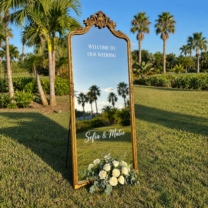 Majestic Welcome Mirror with an ornate gold crown frame, personalized white wedding lettering, and a tropical garden setting in Miami.